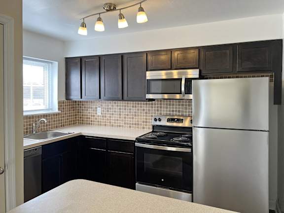 A kitchen with dark brown cabinets and a granite countertop.