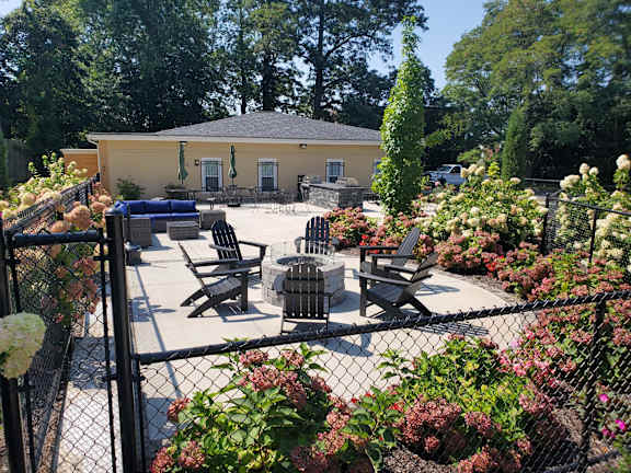 A yellow building with a black fence and flowers in front.