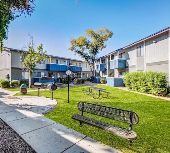 a park with a bench and picnic table in front of a building