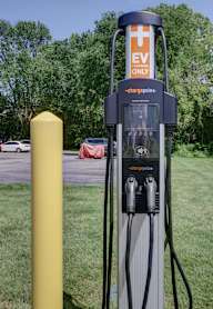A charging station for electric vehicles is located in a grassy area.