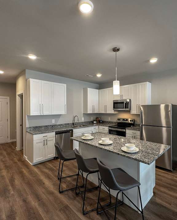 A kitchen with a granite countertop and stainless steel appliances.