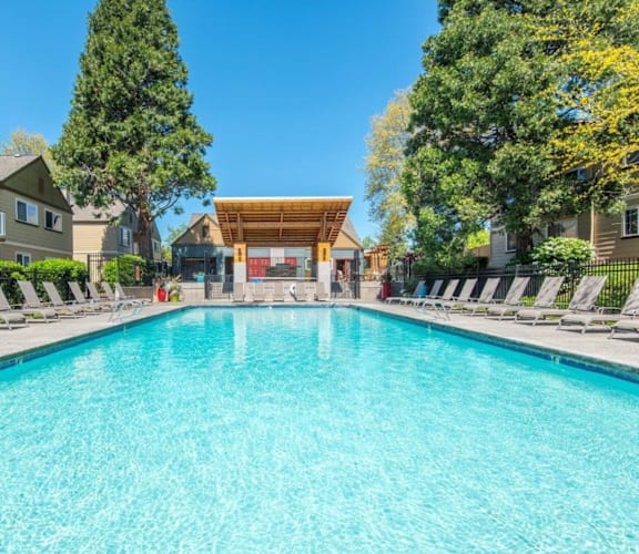 a swimming pool with chaise lounge chairs and a clubhouse in the background