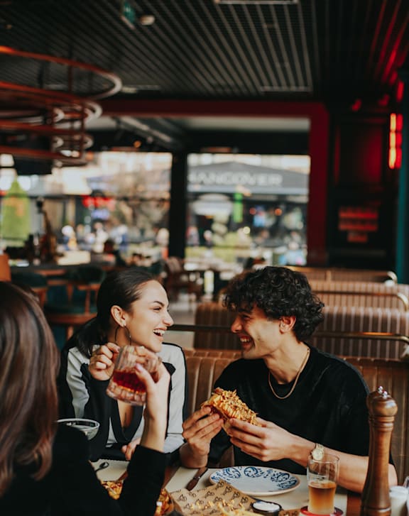 Two people eating pizza in a restaurant.