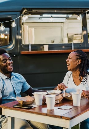 a couple sitting at a table in front of a food truck at Madison at the Arboretum, Texas