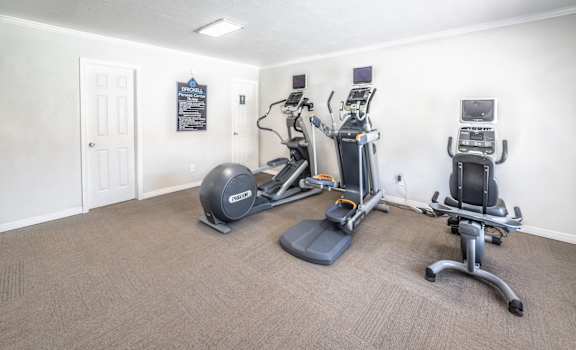 A room with a treadmill, elliptical trainer and a stationary bike.