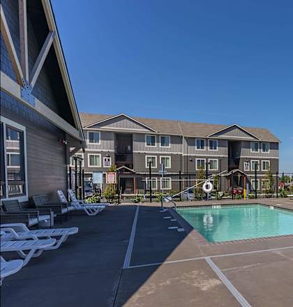 A large outdoor swimming pool with lounge chairs and a building in the background at Cascade Place Apartment Homes, Molalla, OR, 97038