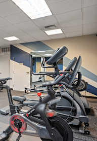 A gym with a row of stationary bikes and a treadmill.