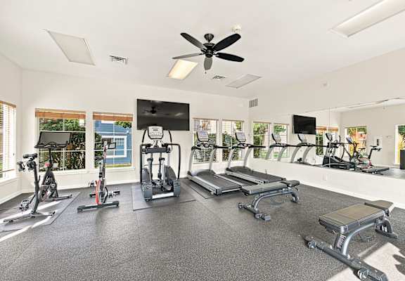 A spacious gym with a variety of equipment including treadmills, stationary bikes, and weight machines.