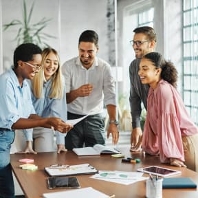 a group of people standing around a table looking at a piece of paper