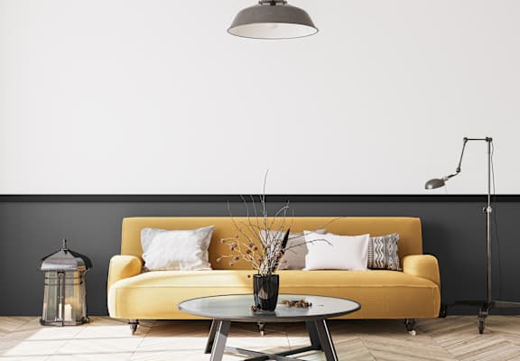 a yellow couch in a living room with a black wall
