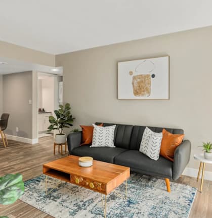 A living room with a grey couch, a wooden coffee table, and a painting on the wall.