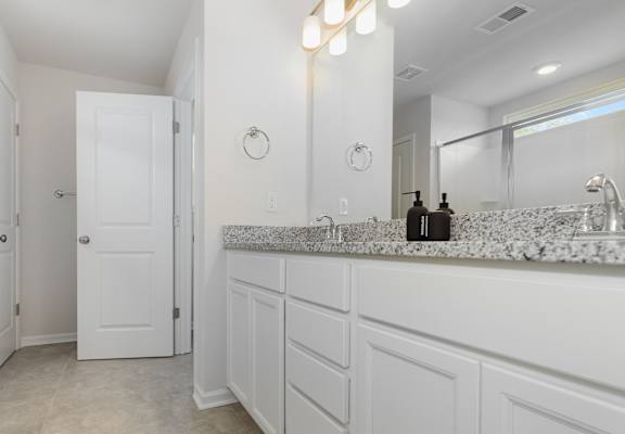 a bathroom with white cabinets and a large mirror