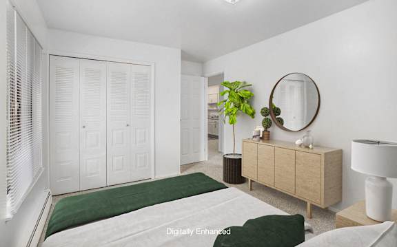 A white bedroom with a bed, dresser, and mirror