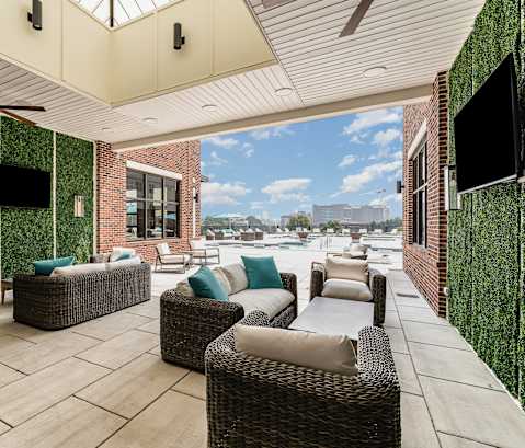 a covered patio with wicker furniture and a flat screen tv