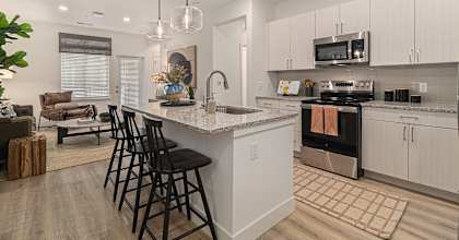 A modern kitchen with a white island and black barstools.