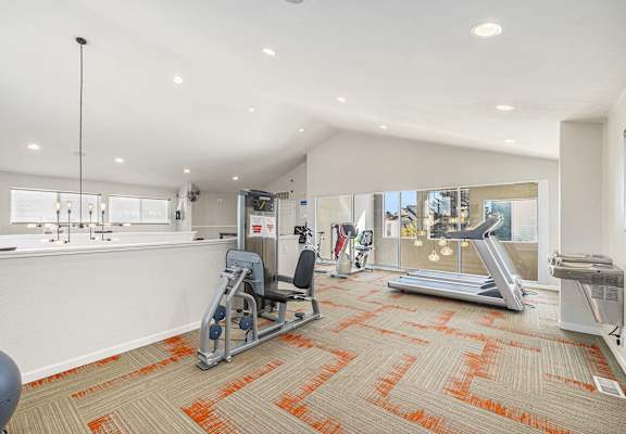 A gym with orange carpeting and various exercise equipment.