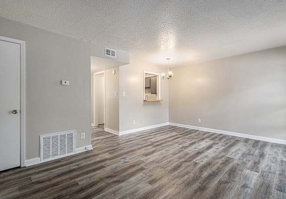 an empty living room with wood flooring and white walls