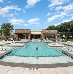a swimming pool with lounge chairs and umbrellas in front of a brick building