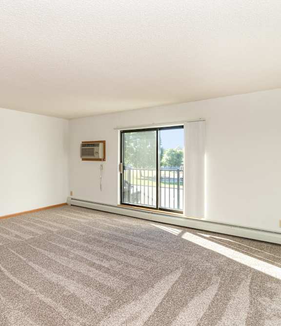 an empty living room with a sliding glass door to a balcony