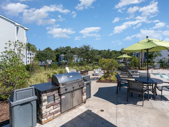 a patio with a grill and tables with umbrellas and a swimming pool
