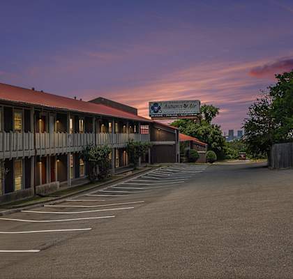 an empty parking lot in front of a motel with a pink sky