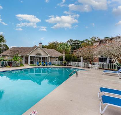 a swimming pool with a house in the background at Litchfield Oaks Apartments, Pawleys Island