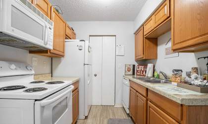 A kitchen with white appliances and wooden cabinets.
