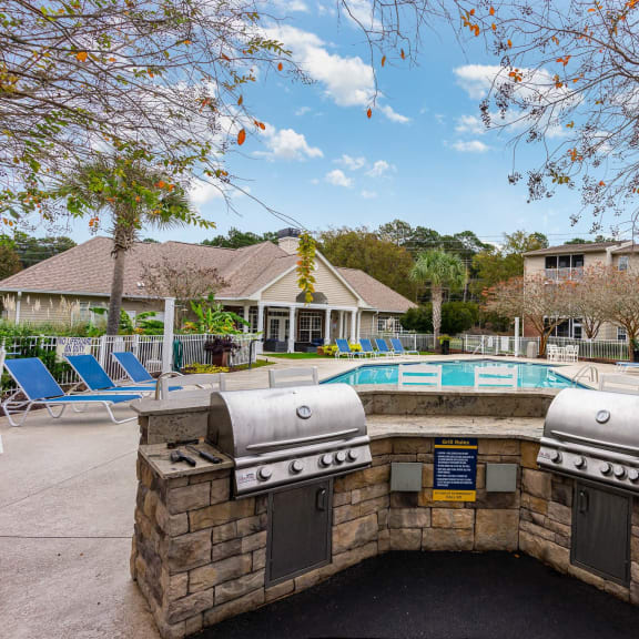 the preserve at ballantyne commons clubhouse with a grill and a pool with chairs at Litchfield Oaks Apartments, Pawleys Island, SC