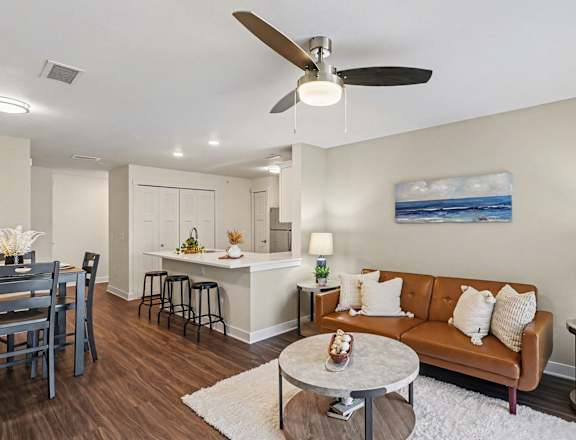 A living room with a brown couch and a ceiling fan at The Grove Apartment Homes, Lincoln, NE