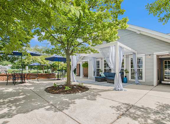 a patio with a tree and a white house