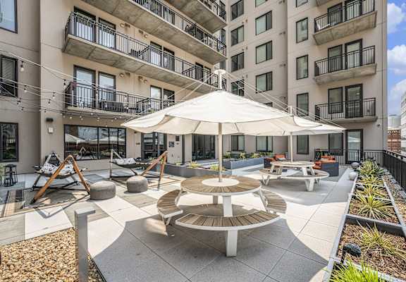 an outdoor patio with tables and an umbrella in an apartment building