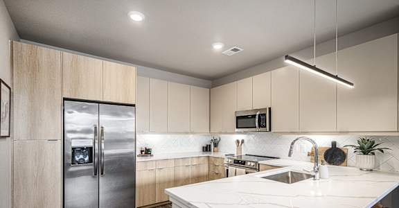 a kitchen with white marble counter tops and a stainless steel refrigerator