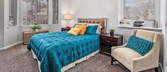 A bedroom with a bed, chair, and ceiling fan.