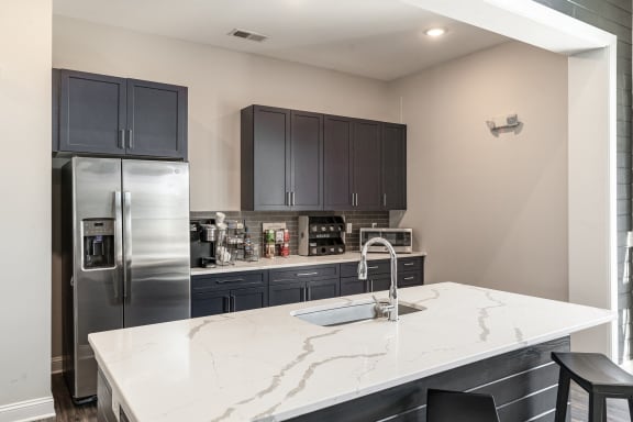 a kitchen with a marble counter top and a stainless steel refrigerator