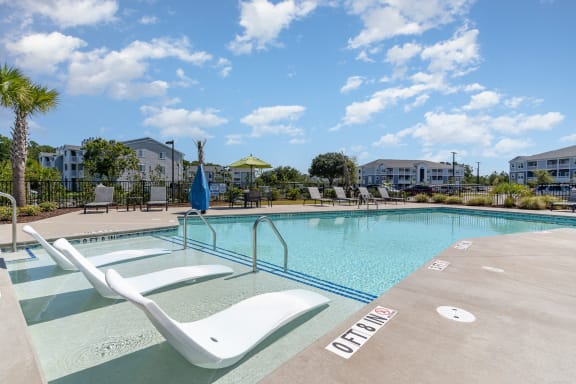 our resort style swimming pool is next to our building with apartment buildings in the background