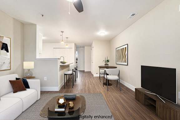 A living room with a white couch, a coffee table, and a television.