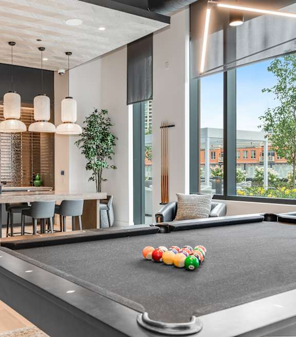 A pool table with a television and a bar area in the background.
