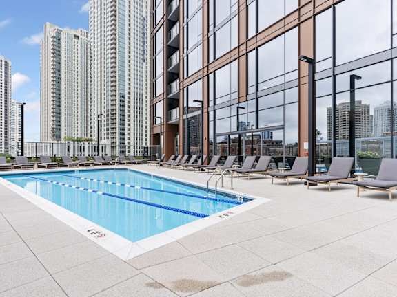 a pool with lounge chairs next to a tall building