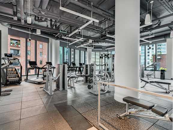 a gym with weights and cardio equipment in a building with tall windows