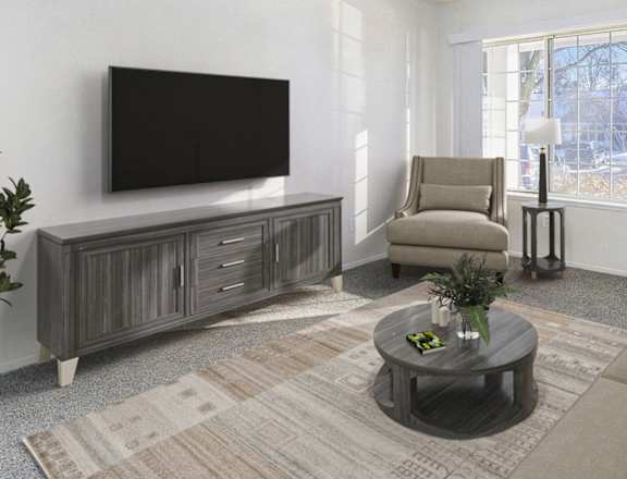 A living room with a grey couch, a flat screen TV, a coffee table, and a potted plant at Newport Village Apartments, Portage, Michigan