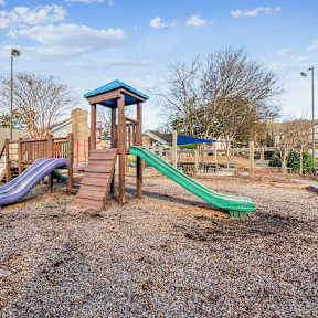 A playground with a purple and green slide and a brown wooden structure.