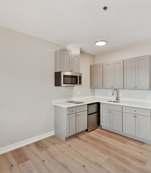 an empty kitchen with white cabinets and a wooden floor