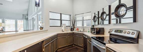 A modern kitchen with dark wood cabinets and stainless steel appliances.