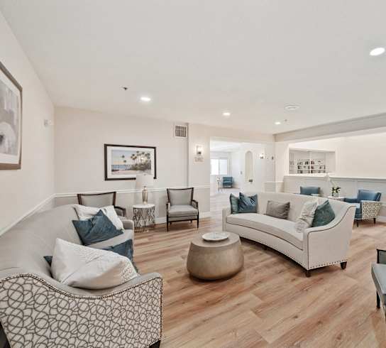 a living room with couches and chairs and a kitchen
