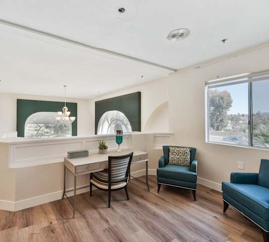 a living room with a desk and chairs and a large window