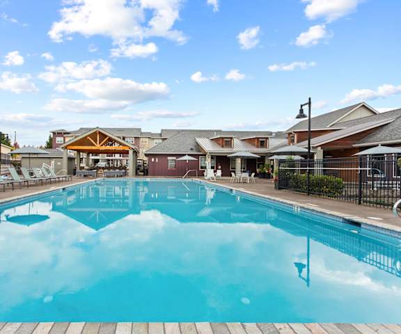 A large outdoor swimming pool with a wooden deck and lounge chairs.