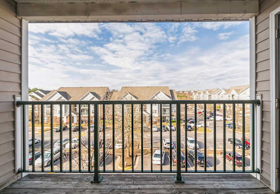 A view from a balcony looking out at a parking lot and houses.