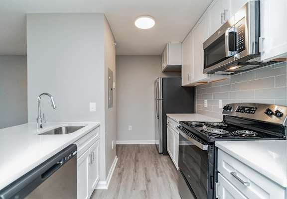 an empty kitchen with white cabinets and stainless steel appliances