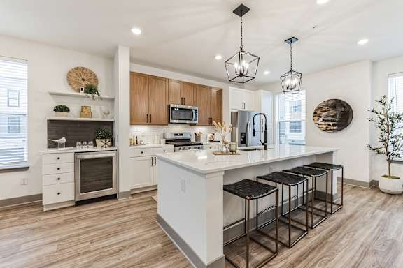 an open kitchen with a large island with bar stools at Meridian at CityPlace in Woodbury, MN 55125