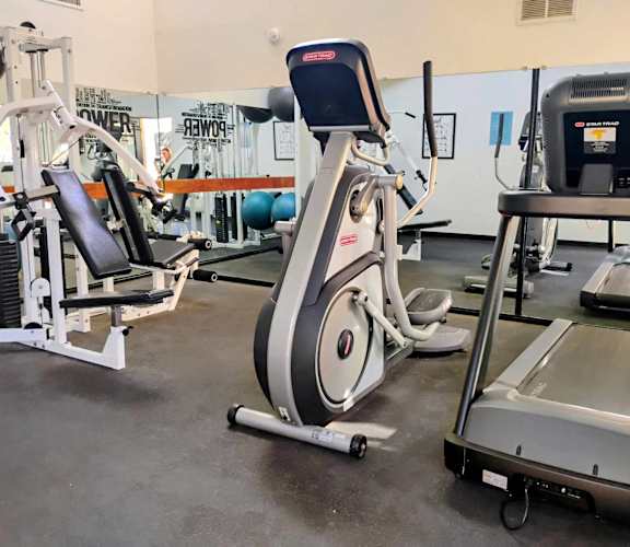 A gym with a rowing machine, a leg press machine, and a weight bench.